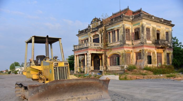 Historic building with a bulldozer outside on a construction site, under a clear sky.
