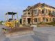 Historic building with a bulldozer outside on a construction site, under a clear sky.