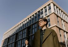 ÚLTIMA HORA: Restrepo & Associates nombra a James Barnett vicepresidente Two stylish women in coats in a business district with modern architecture.