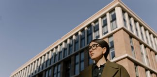 Two stylish women in coats in a business district with modern architecture.