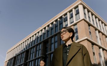 Two stylish women in coats in a business district with modern architecture.