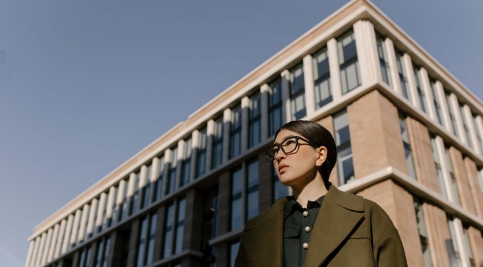 Two stylish women in coats in a business district with modern architecture.