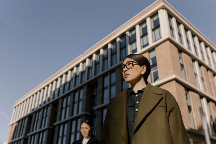 ltima-hora-restrepo-associates-nombra-a-james-bar Two stylish women in coats in a business district with modern architecture.