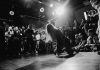 Dynamic black and white shot of a dancer performing to an enthralled crowd in a lively venue.