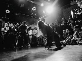 Dynamic black and white shot of a dancer performing to an enthralled crowd in a lively venue.