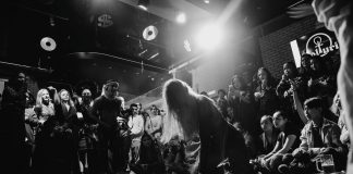 Dynamic black and white shot of a dancer performing to an enthralled crowd in a lively venue.