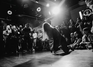 Dynamic black and white shot of a dancer performing to an enthralled crowd in a lively venue.