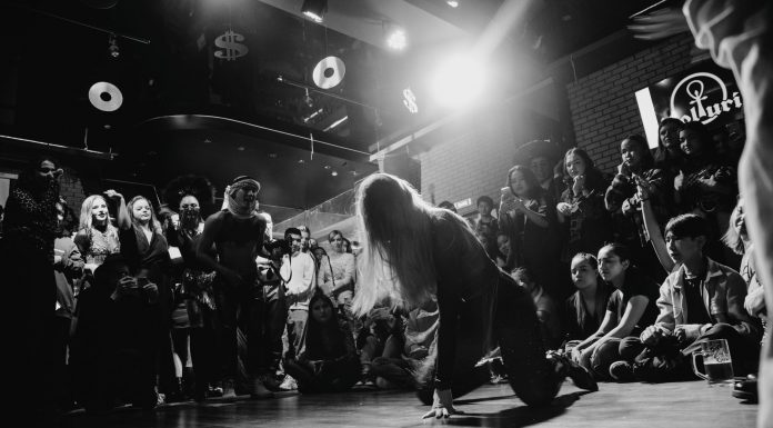 ÚLTIMA HORA: Shyne, Barrington Levy y Lil’ Cease tocarán en el Loew’s renovado Dynamic black and white shot of a dancer performing to an enthralled crowd in a lively venue.