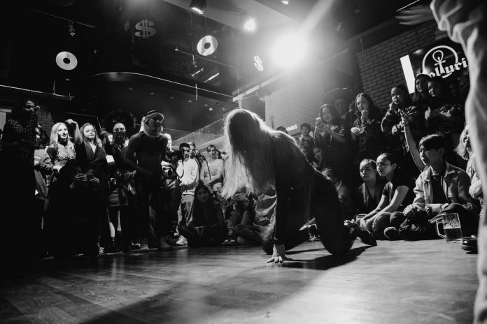 Dynamic black and white shot of a dancer performing to an enthralled crowd in a lively venue.