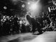 ÚLTIMA HORA: Shyne, Barrington Levy y Lil’ Cease tocarán en el Loew’s renovado Dynamic black and white shot of a dancer performing to an enthralled crowd in a lively venue.