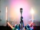 Retro microphone on a stage with colorful lights and a drum set, perfect for music themes.