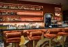 A chic bar interior showcasing a sophisticated design with plush seating and a well-stocked counter.