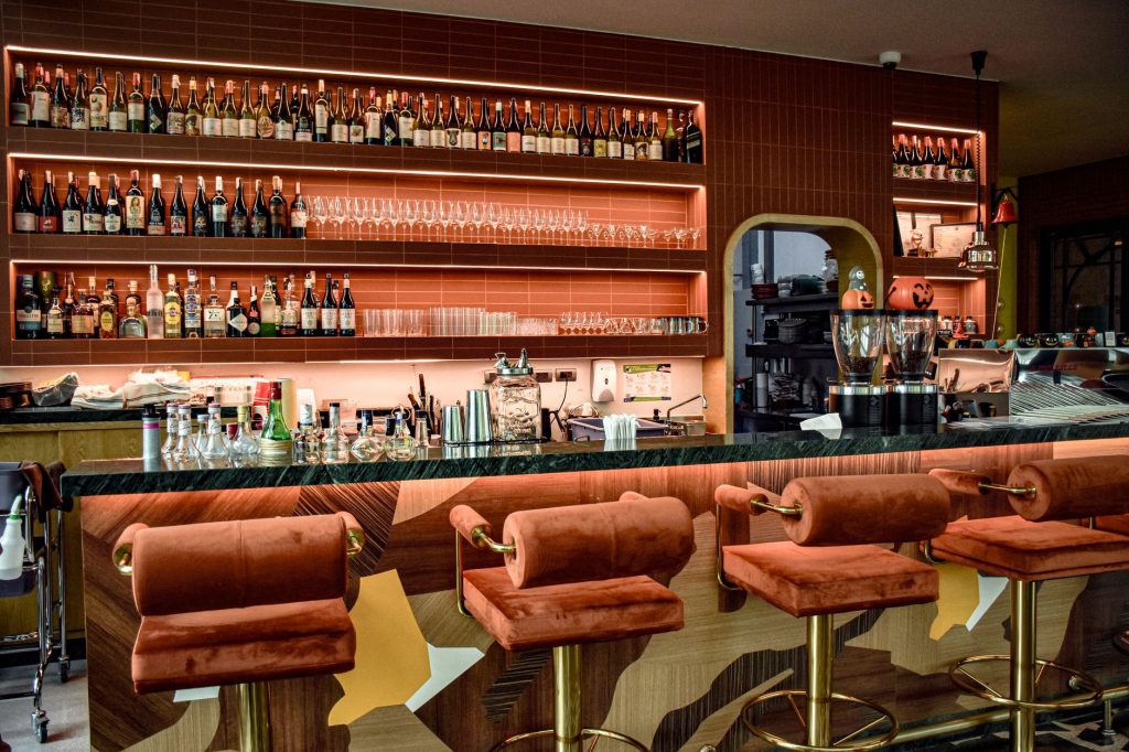 A chic bar interior showcasing a sophisticated design with plush seating and a well-stocked counter.