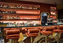 A chic bar interior showcasing a sophisticated design with plush seating and a well-stocked counter.