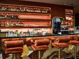 A chic bar interior showcasing a sophisticated design with plush seating and a well-stocked counter.