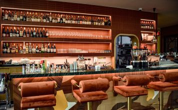 ÚLTIMA HORA: Tu bar en Hoboken según tu signo zodiacal A chic bar interior showcasing a sophisticated design with plush seating and a well-stocked counter.