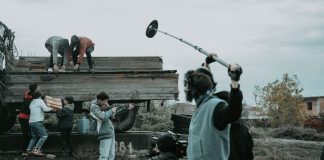 Film crew working outdoors, capturing scenes with camera and boom mic.
