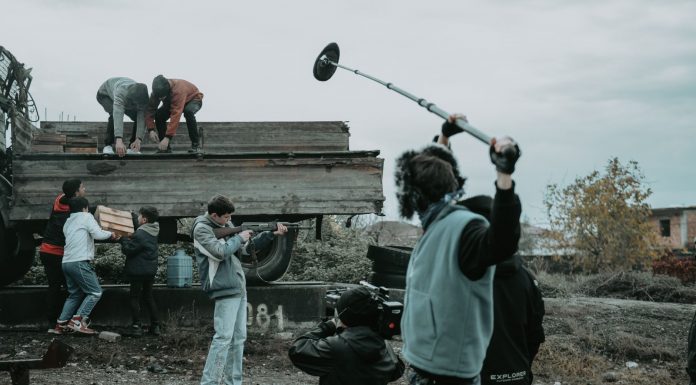 Film crew working outdoors, capturing scenes with camera and boom mic.