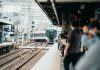 A train arriving at a bustling Japanese station filled with waiting passengers.