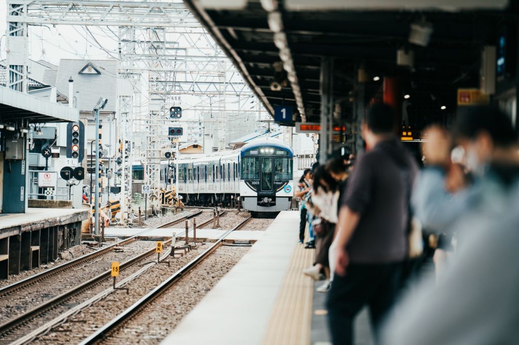 A train arriving at a bustling Japanese station filled with waiting passengers.