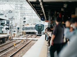 A train arriving at a bustling Japanese station filled with waiting passengers.