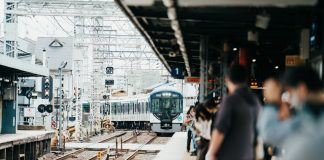 A train arriving at a bustling Japanese station filled with waiting passengers.