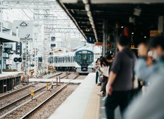A train arriving at a bustling Japanese station filled with waiting passengers.