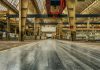 Wide view of an empty industrial warehouse with visible cranes and metal structures.