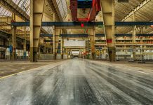Wide view of an empty industrial warehouse with visible cranes and metal structures.