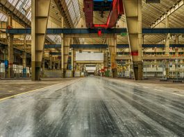 Wide view of an empty industrial warehouse with visible cranes and metal structures.