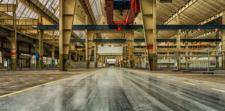 Wide view of an empty industrial warehouse with visible cranes and metal structures.