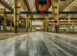 Wide view of an empty industrial warehouse with visible cranes and metal structures.