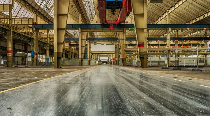 Wide view of an empty industrial warehouse with visible cranes and metal structures.