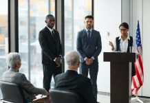 Professional speakers presenting at a conference in a modern room with glass windows.