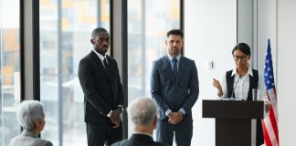 Professional speakers presenting at a conference in a modern room with glass windows.