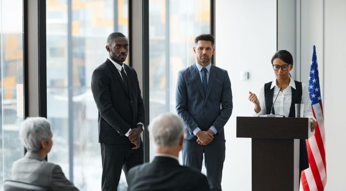 Professional speakers presenting at a conference in a modern room with glass windows.
