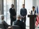 Mayor Solomon Urges School Board to Reject Superintendent Contract Extension Professional speakers presenting at a conference in a modern room with glass windows.