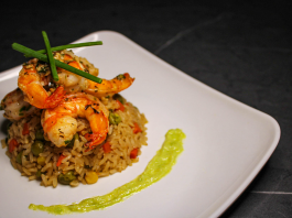 Savory prawn fried rice garnished with chives on a stylish white plate, capturing gourmet cuisine.