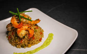 Savory prawn fried rice garnished with chives on a stylish white plate, capturing gourmet cuisine.