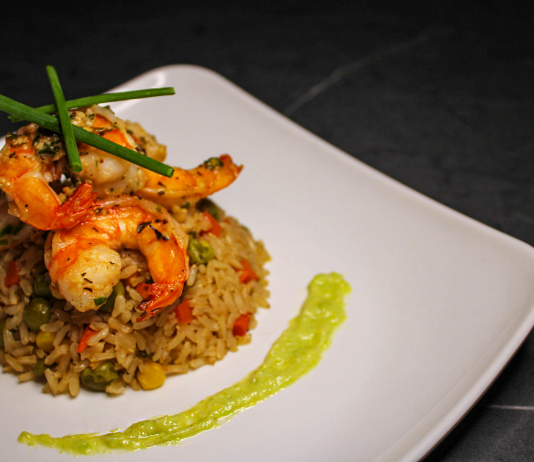 Savory prawn fried rice garnished with chives on a stylish white plate, capturing gourmet cuisine.