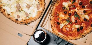Top view of delicious pizzas in boxes with a refreshing drink, perfect for a cozy meal.