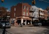 Street view of Joe's Pizza on a sunny day in Brooklyn, showcasing the lively urban atmosphere.
