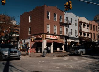 La Mejor Pizza en West New York en 2026: Guía Definitiva de las Pizzerías Imperdibles Street view of Joe's Pizza on a sunny day in Brooklyn, showcasing the lively urban atmosphere.