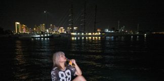 Los Mejores Bares en Jersey City: Guía 2026 para Salir de Noche en el Condado de Hudson Woman sitting by the waterfront at night with city lights in the background.