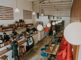Bright and inviting coffee shop interior with people working, featuring stylish decor and pendant lighting.
