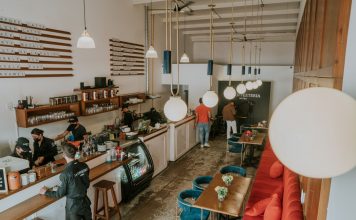 Bright and inviting coffee shop interior with people working, featuring stylish decor and pendant lighting.