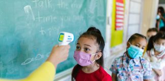 Las Mejores Escuelas en West New York para 2026: Guía Completa para Familias Children wearing masks have their temperature checked in a classroom setting.