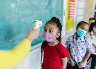 Las Mejores Escuelas en West New York para 2026: Guía Completa para Familias Children wearing masks have their temperature checked in a classroom setting.