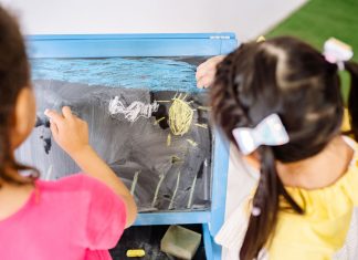 Children enjoying drawing on a blackboard in a vibrant classroom setting, highlighting creativity and education.