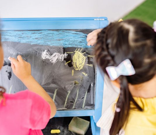 Children enjoying drawing on a blackboard in a vibrant classroom setting, highlighting creativity and education.